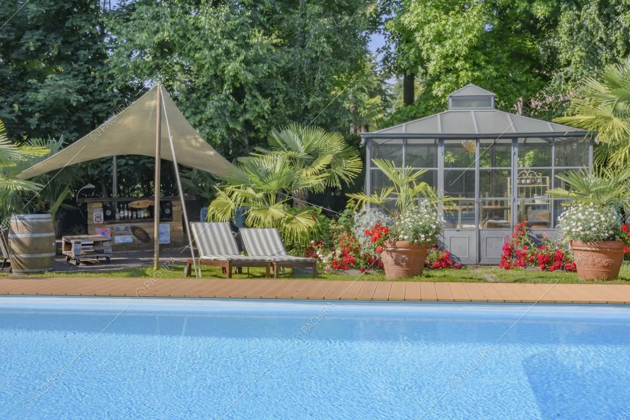 Serra in vetro con fiori e piante in vaso sul bordo della piscina