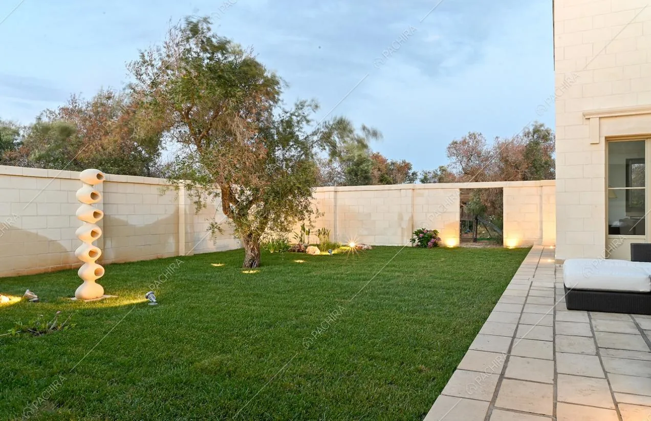 Giardino curatissimo con ulivo, circondato da mura in pietra bianche