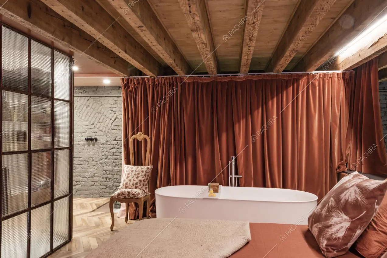 Vasca nella camera da letto con tendaggio in velluto, vetrata industriale e pareti in mattoni