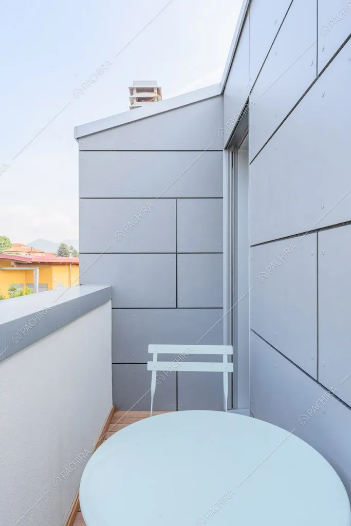 Tavolo e sedia bianchi sul balcone con vista sugli esterni grigi