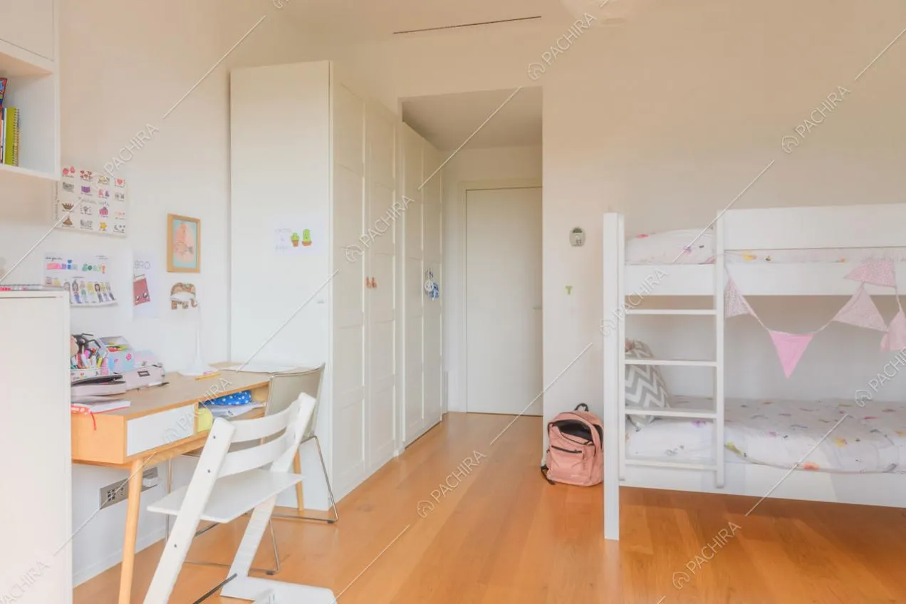Camera dei bambini con letto a castello bianco, pavimento in parquet e scrivania