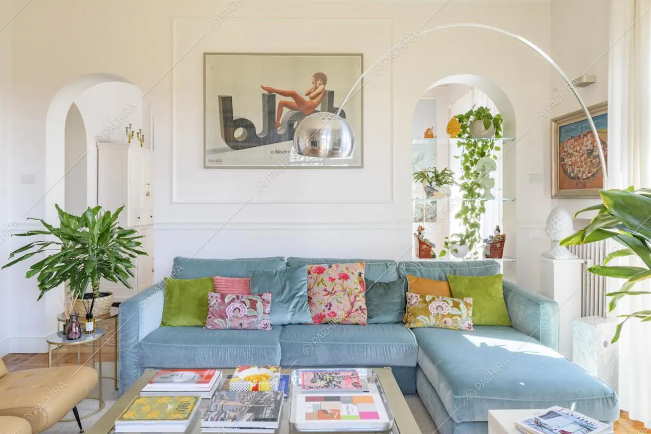 Sala con boiserie alle pareti, arredamento di design e divano angolare azzurro