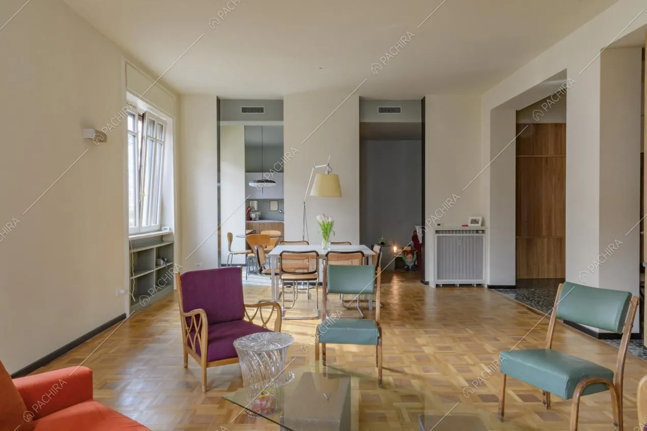 Salotto dalle pareti bianche con pavimento in parquet e tavolo da pranzo bianco