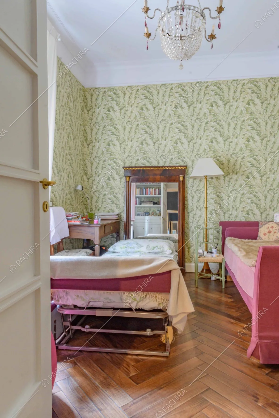 Camera da letto con lampadario antico, carta da parati verde e pavimento in parquet