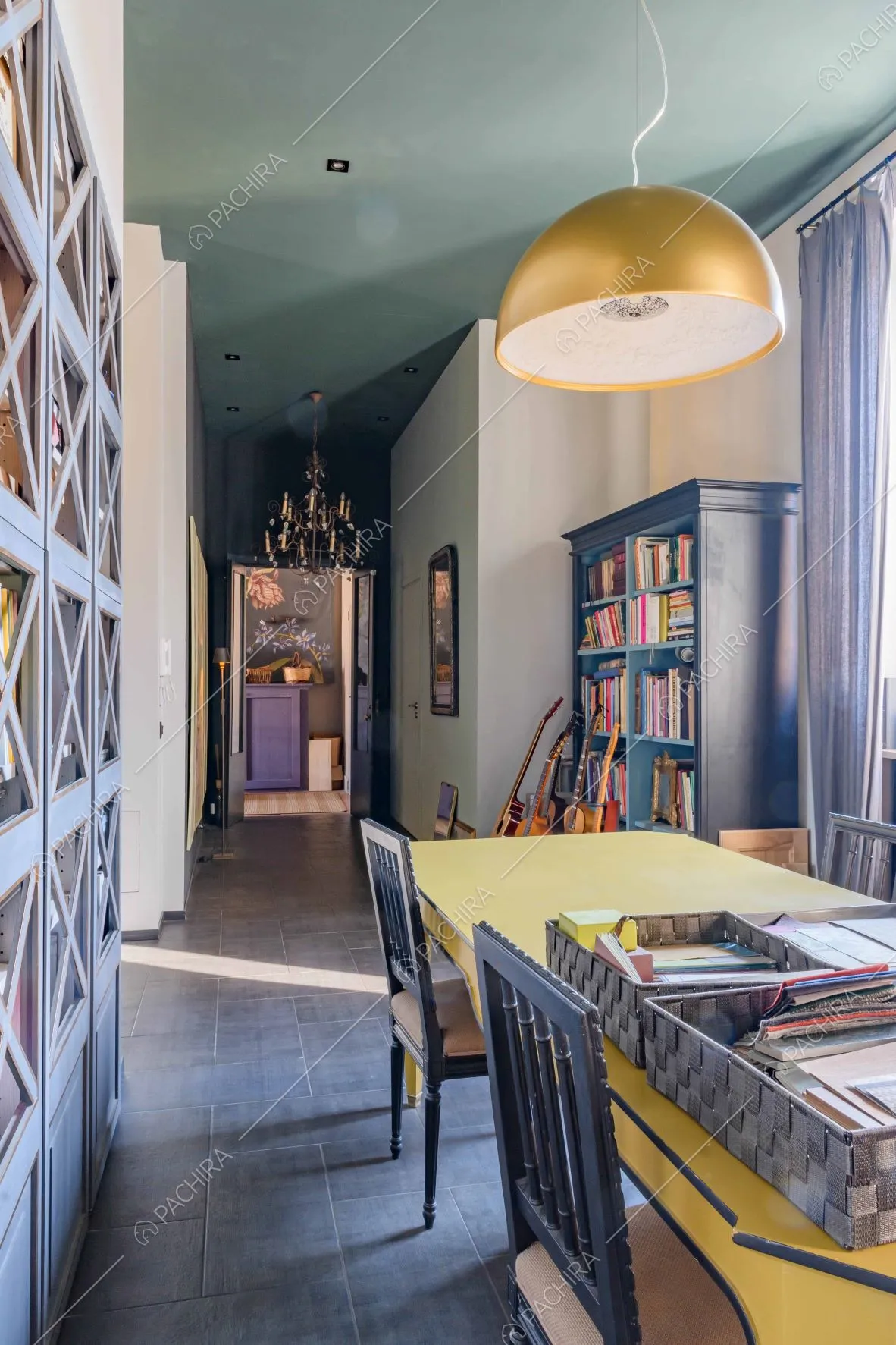 Libreria e scrivania gialla nello studio dal soffitto blu petrolio