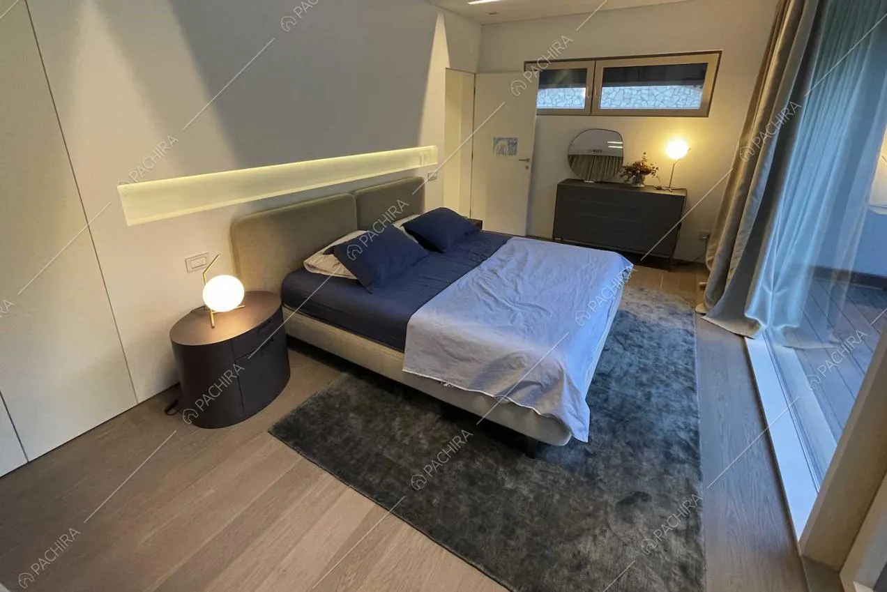 Camera da letto con pavimento in parquet, pareti bianche e ampie vetrate