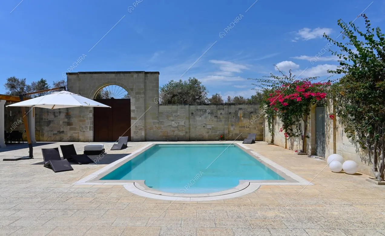 Nel cortile della villa circondata da mura in pietra, meravigliosa piscina con ombrellone e lettini