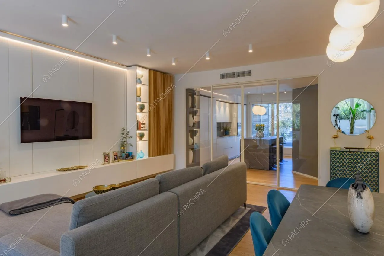 Divano e tavolo grigio nella zona living con vista sulla cucina tramite porta-finestra