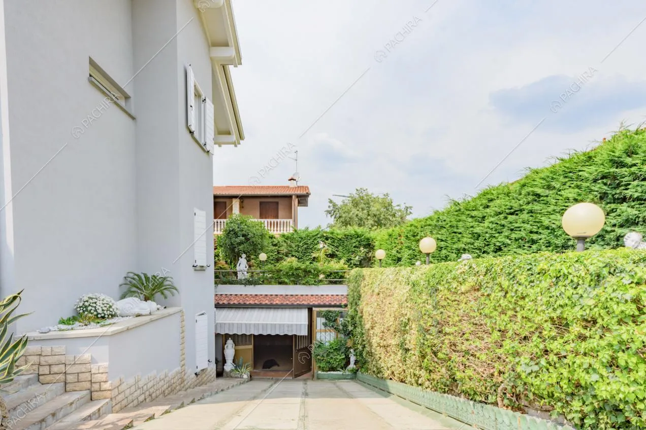 Siepe, esterni grigi della villa e veranda