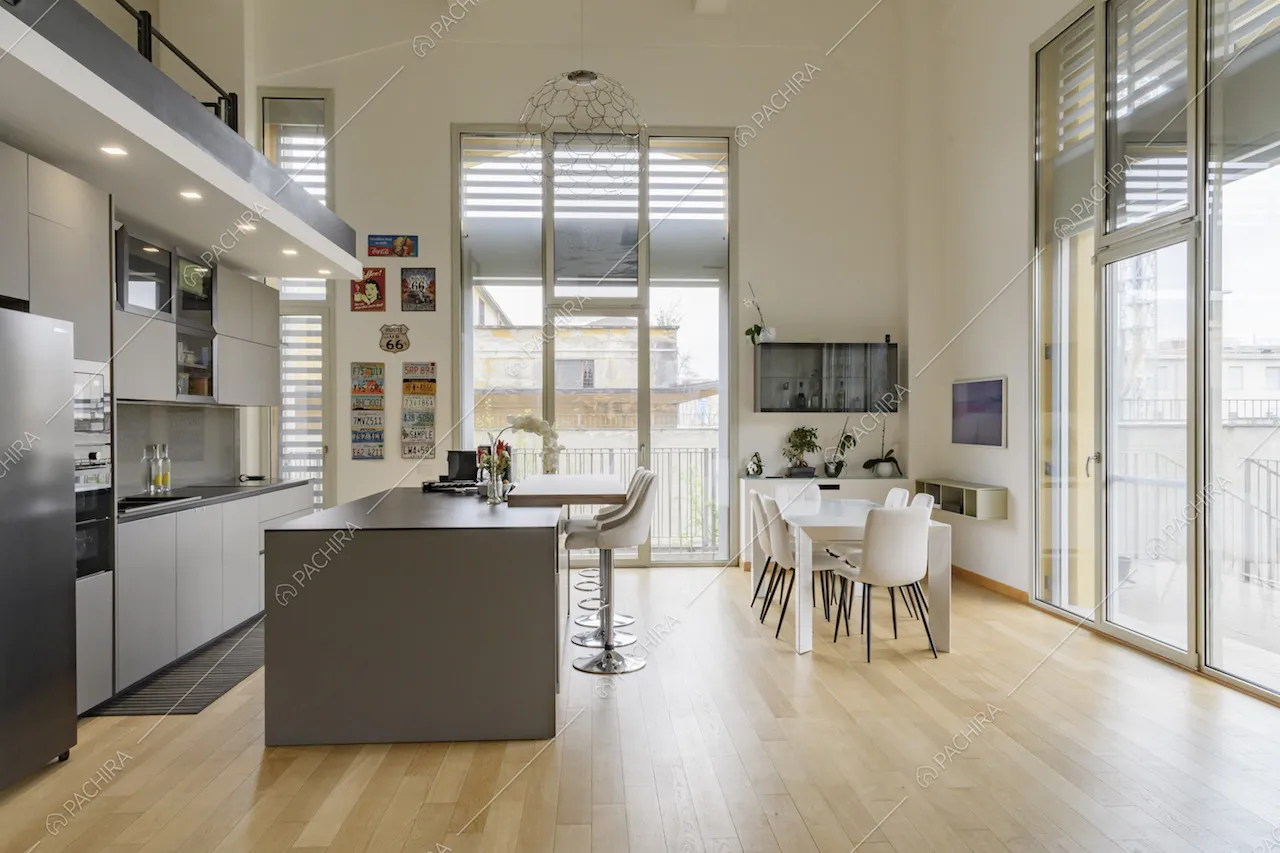Cucina a vista con isola dall'alto soffitto bianco e dal pavimento in parquet