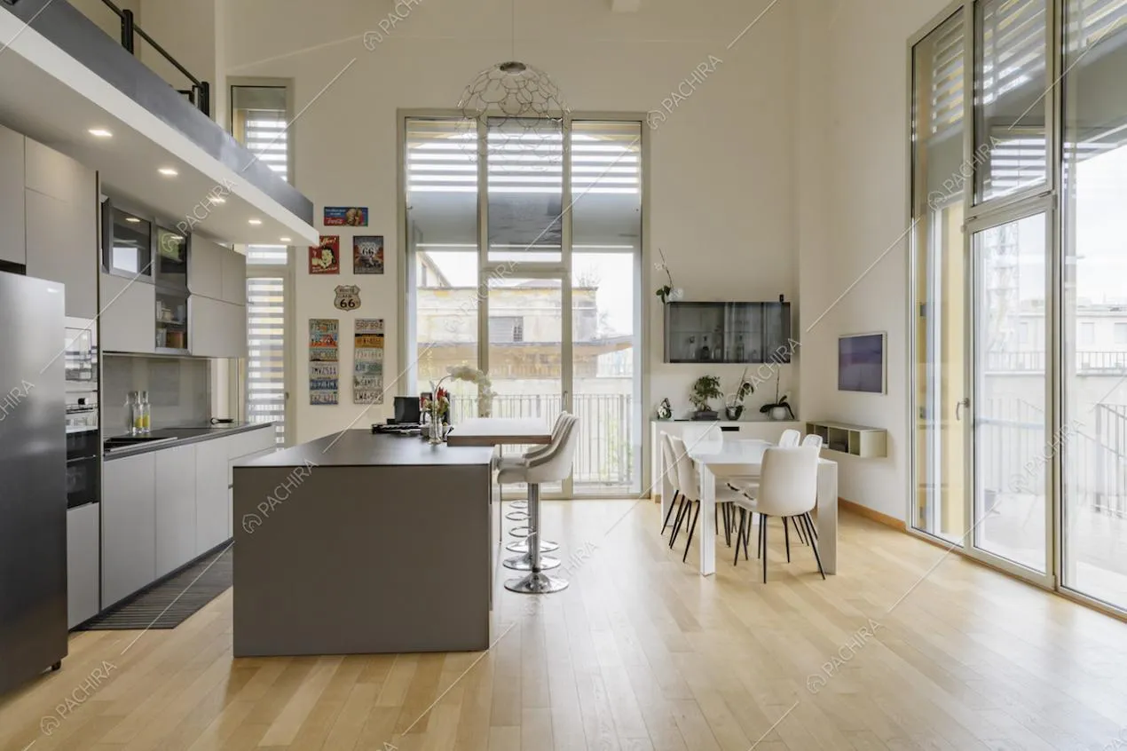 Cucina a vista con isola dall'alto soffitto bianco e dal pavimento in parquet