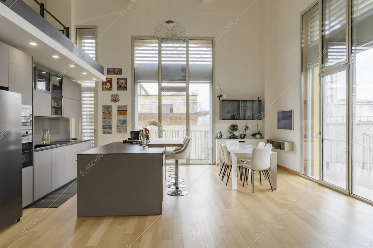 Cucina a vista con isola dall'alto soffitto bianco e dal pavimento in parquet