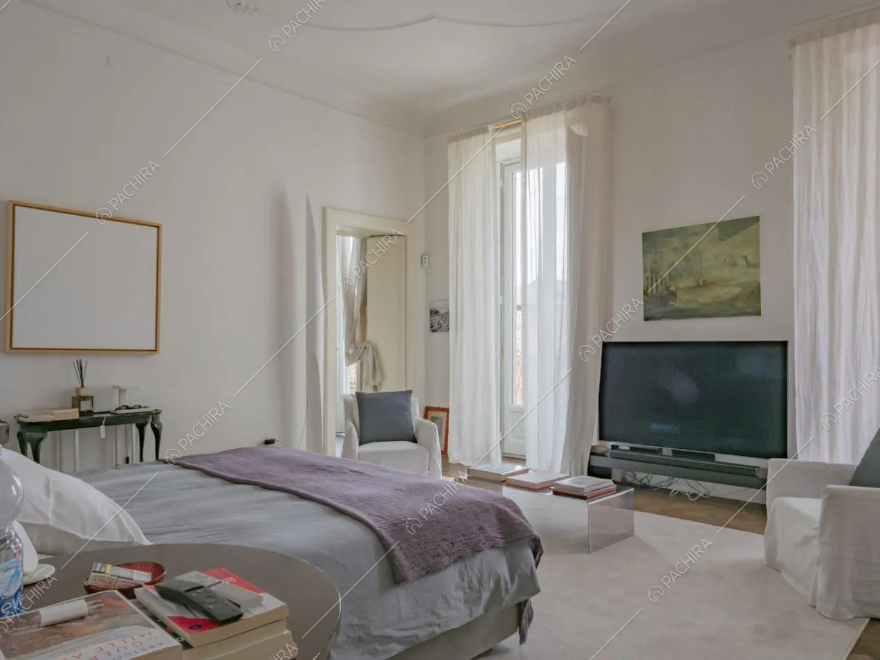 Televisore di fronte al letto matrimoniale e grande tappeto color chiaro