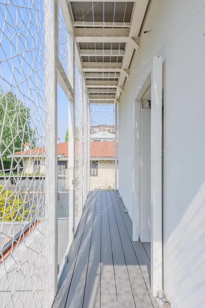 Balcone con parapetto geometrico bianco e pavimento in parquet da esterni
