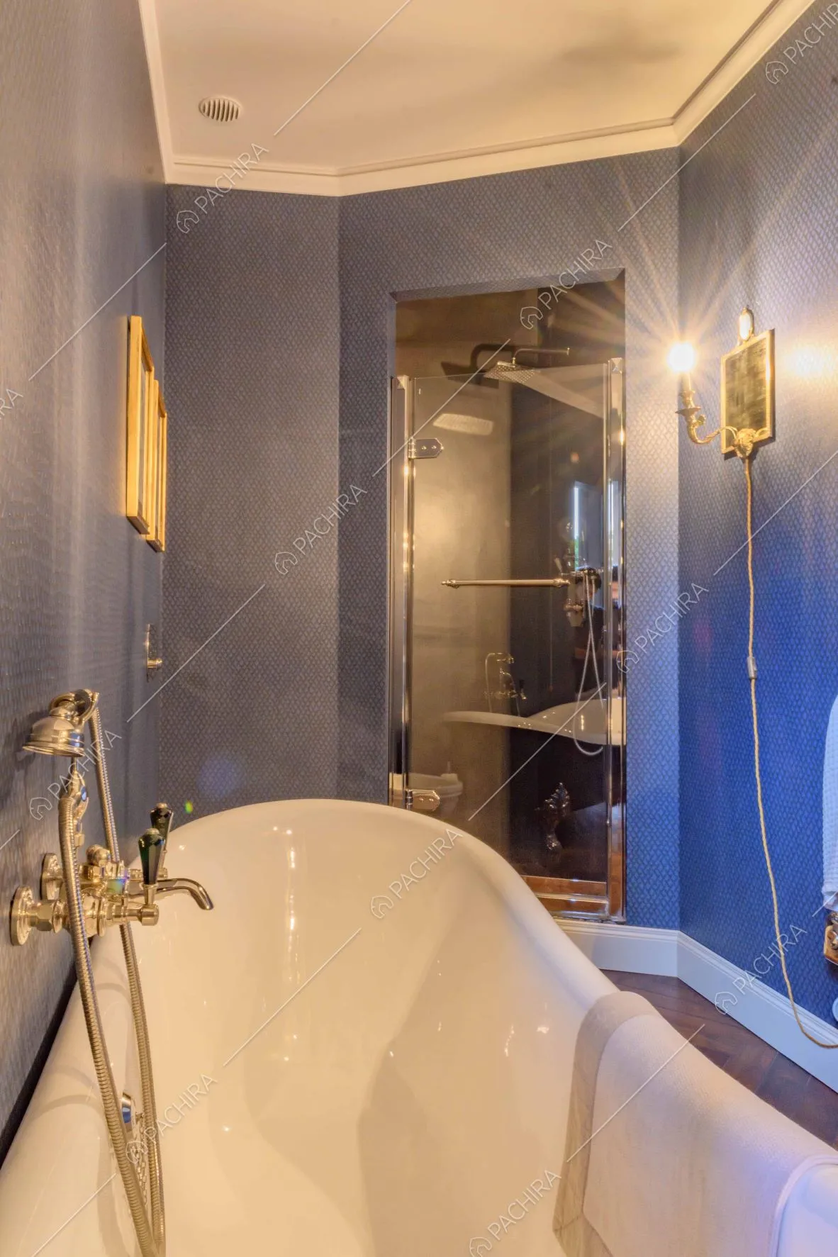 Vasca e box doccia nel bagno dalle pareti blu e dal pavimento in parquet a spina di pesce 