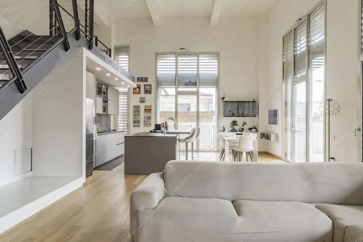 Salotto con pavimento in parquet, divano angolare e cucina a vista con isola