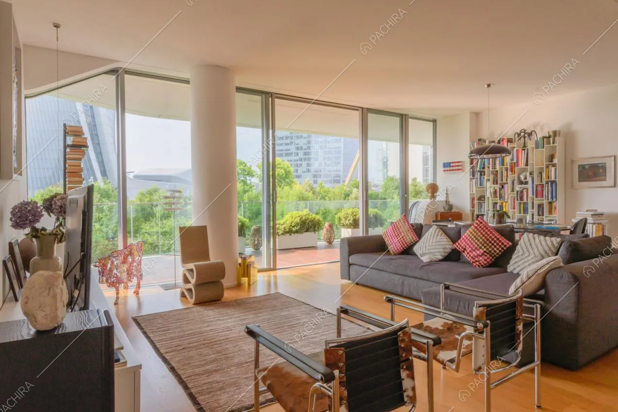Grande zona living con pavimento in parquet, vetrate e pareti bianche