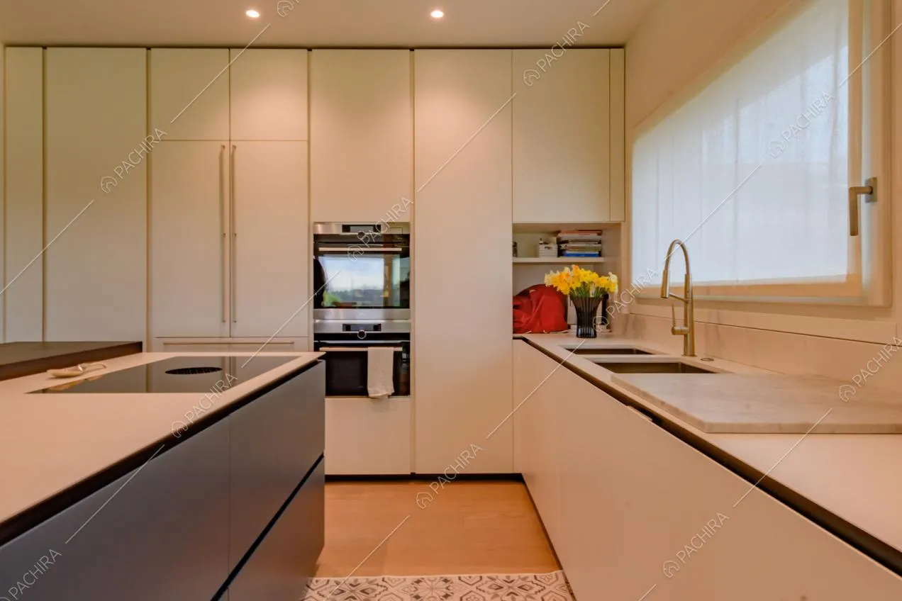 Cucina a isola bianca con fornelli a induzione e pavimento in parquet
