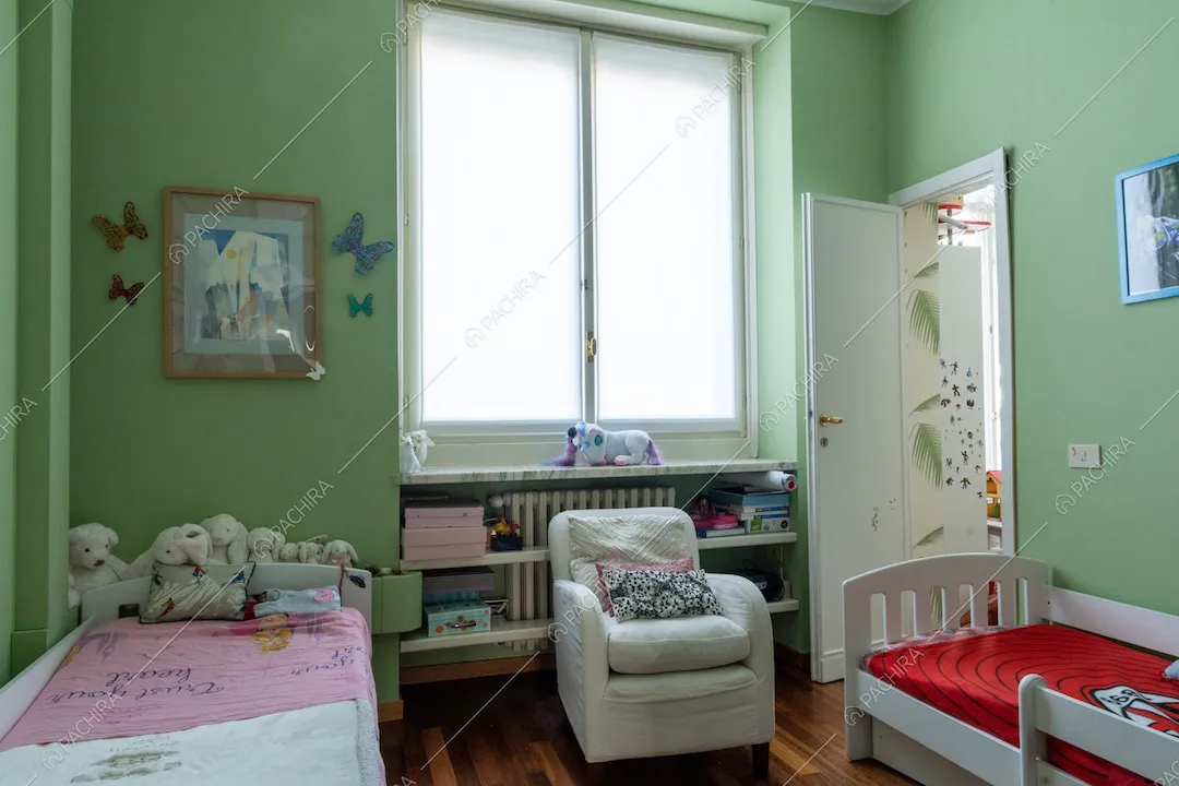 Camera da letto da bambini dalle pareti verdi, con pavimento in parquet e due letti