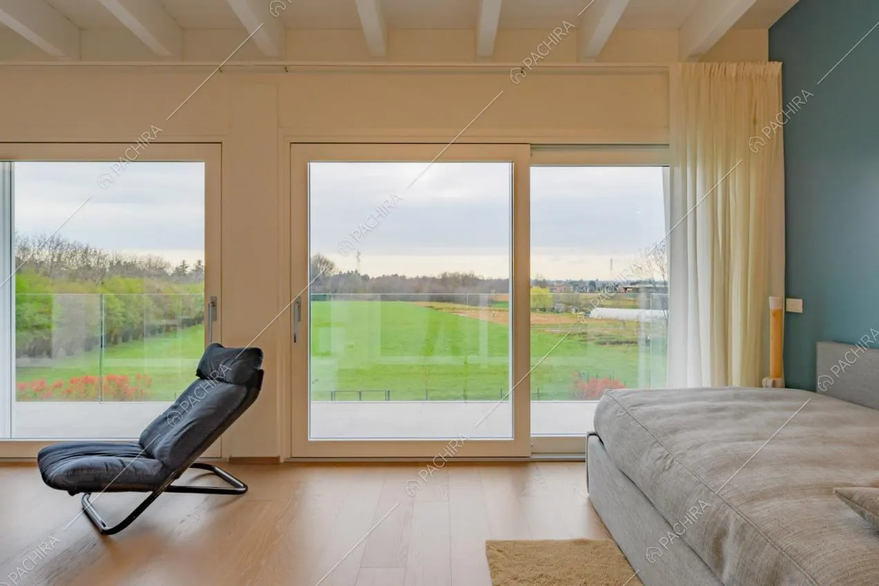 Porte-finestre scorrevoli conducono alla terrazza, letto grigio e pavimento in parquet