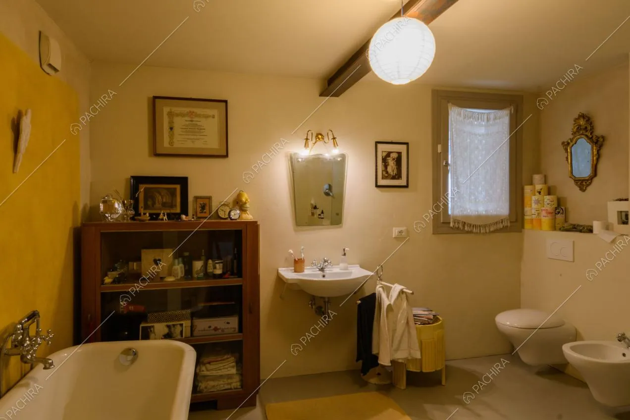 Bagno con vasca, parete gialla délabré e pavimento grigio in resina
