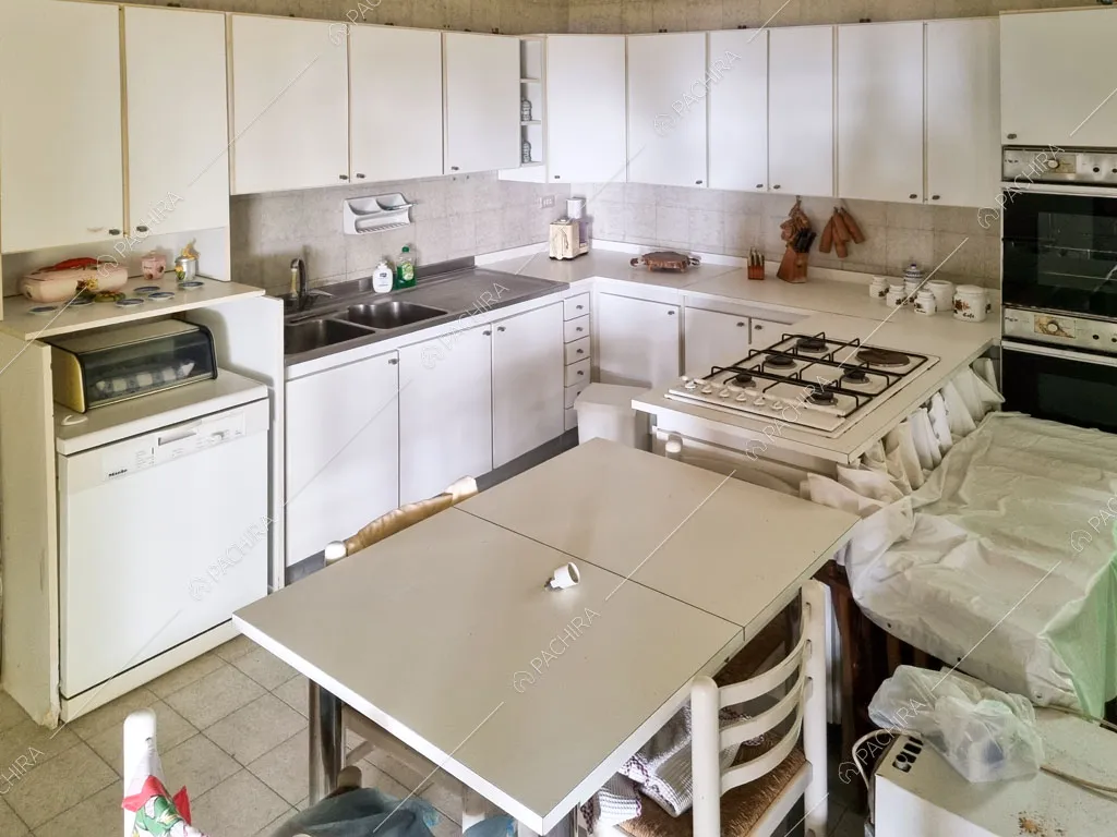 Cucina a parete con fornelli a gas e pavimento in piastrelle bianche