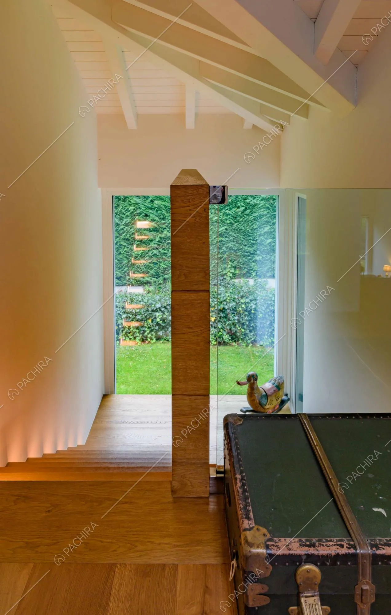 Dalle scale in legno con pianerottolo unico vista sul giardino tramite le ampie vetrate