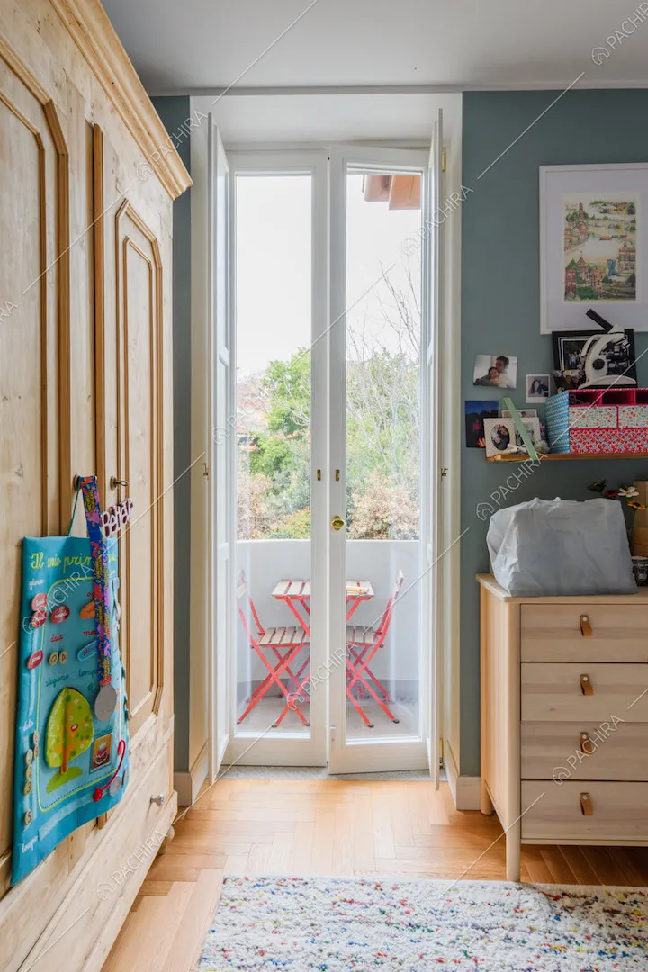 Porta-finestra che conduce al balcone con tavolo e sedie da esterni nella camera da letto