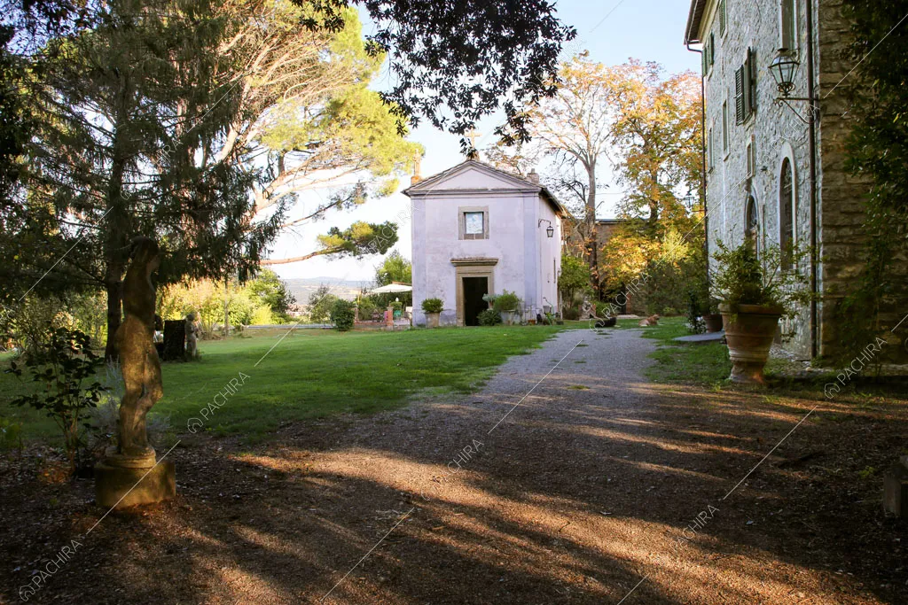 Dal grande giardino vista sugli esterni in pietra della casa e sulla cappella