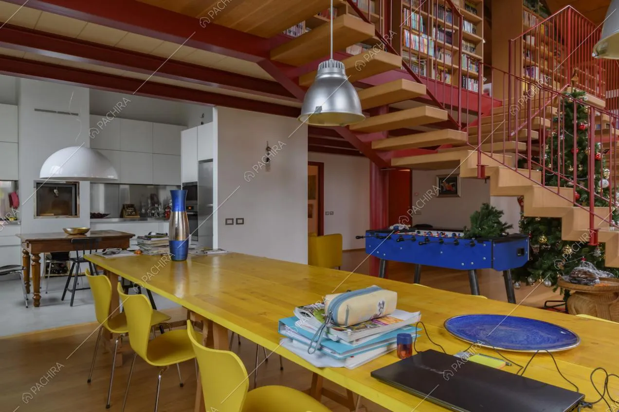 Tavolo giallo in legno nel salone della location e vista sulla cucina a parete
