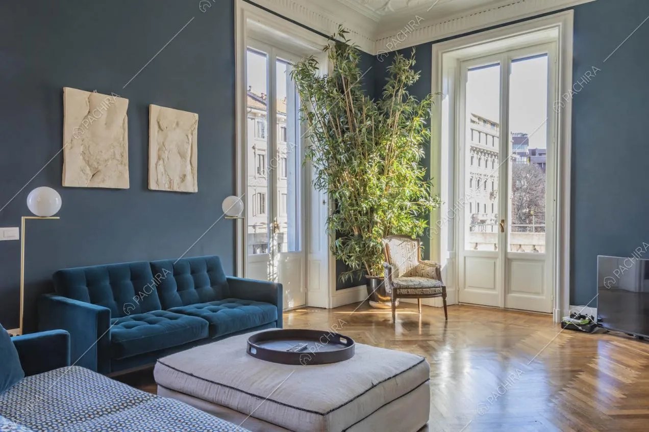 Divani blu nel salotto con pavimento in parquet, porte-finestre e boiserie sul soffitto