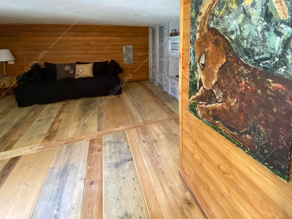 Pavimento in parquet nella sala con divano nero dello chalet Thar, location in stile rustico ad Aosta