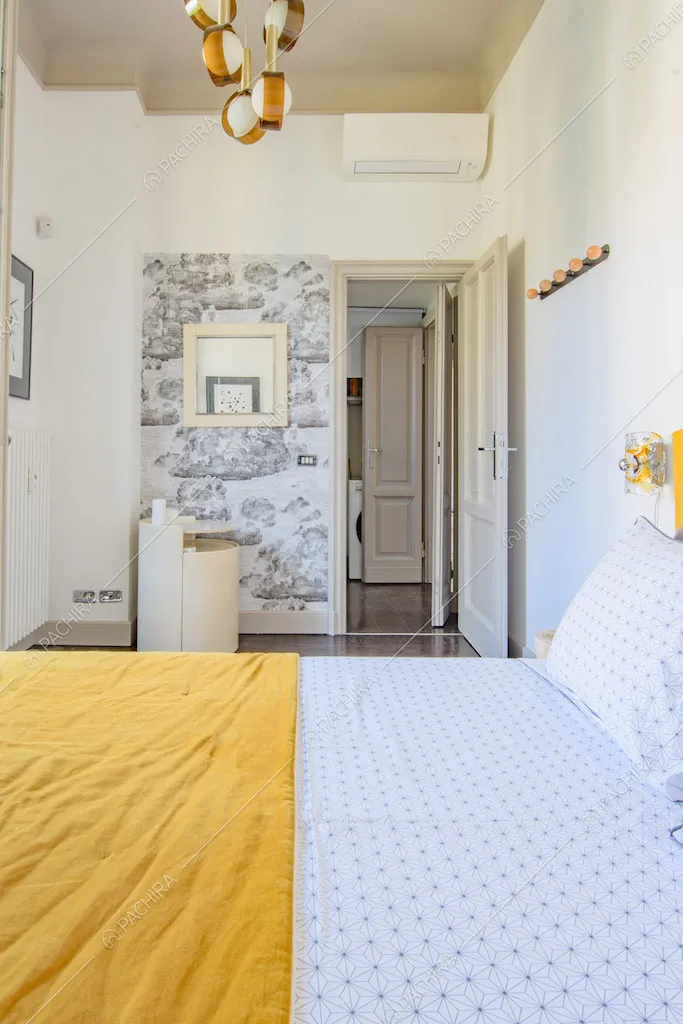 Letto matrimoniale nella camera con carta da parati e pavimento in parquet