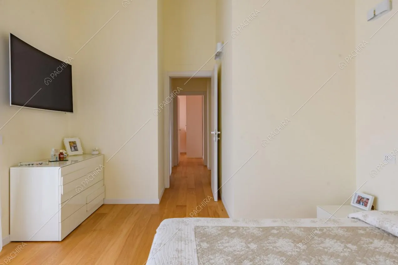 Letto matrimoniale nella camera con pavimento in parquet e televisore