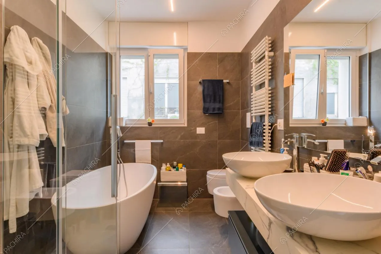 Grande bagno con pavimento e pareti piastrelle grigie, doppio lavandino e vasca