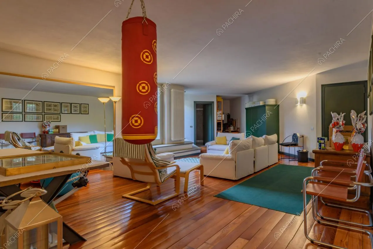 Grande sala con pavimento in parquet, sacco da boxe e pareti bianche