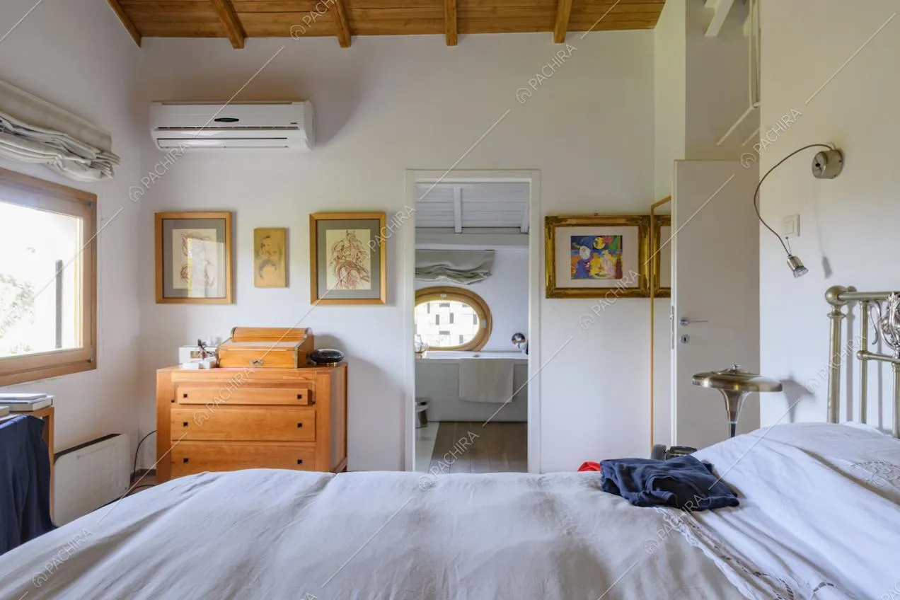 Letto matrimoniale, cassettiera in legno e scorcio sul bagno