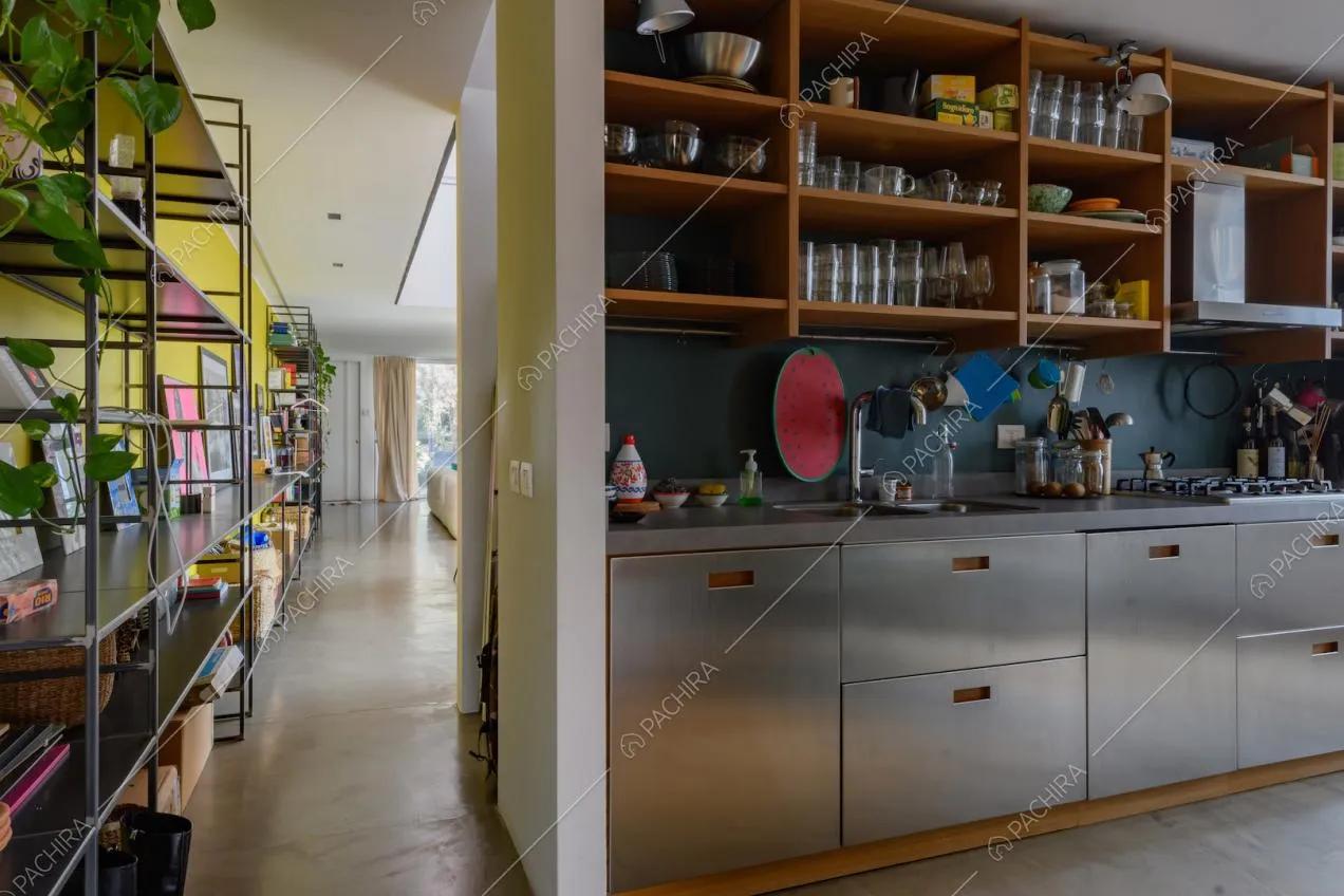 Cucina a parete in acciaio con fornelli a gas e vista sulla luminosa zona living
