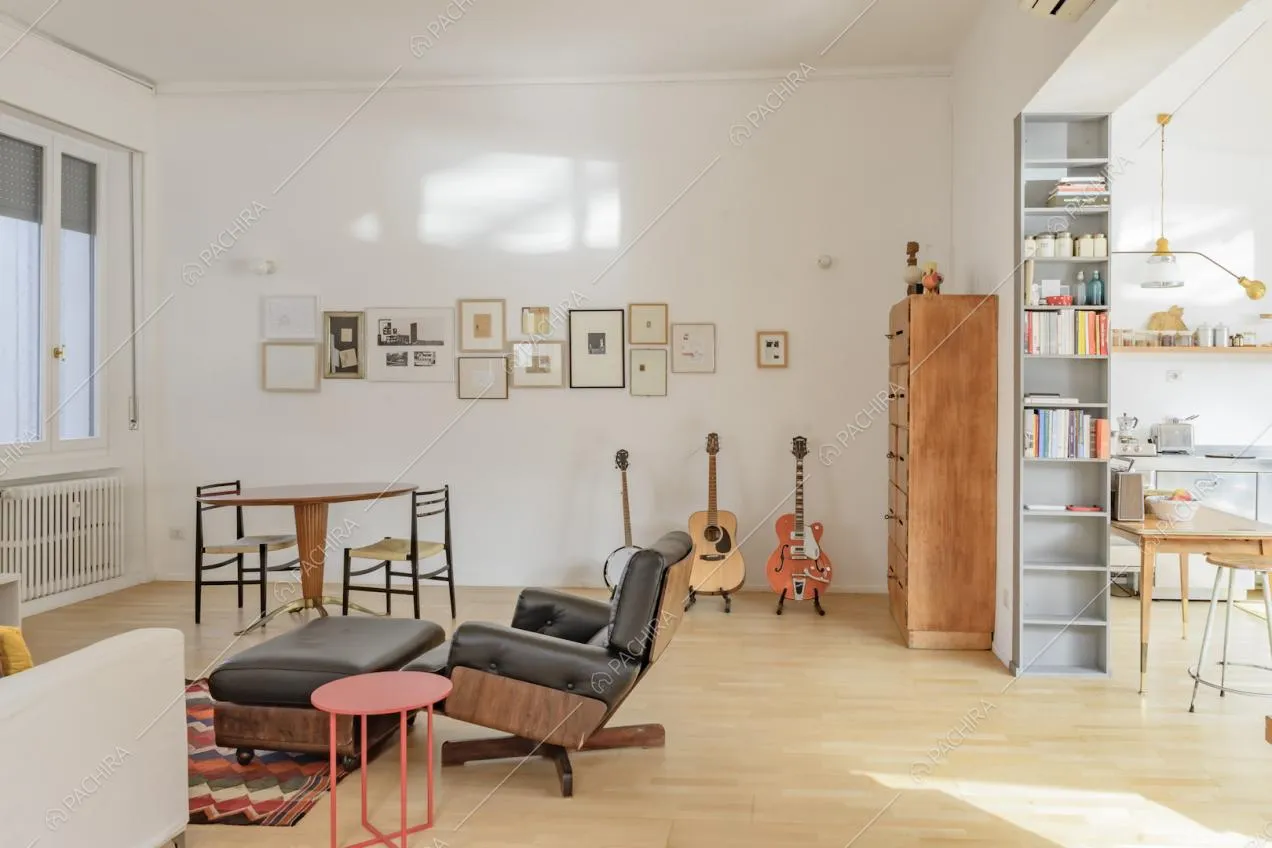 La zona living con tavolo in legno, pareti bianche e chitarre esposte