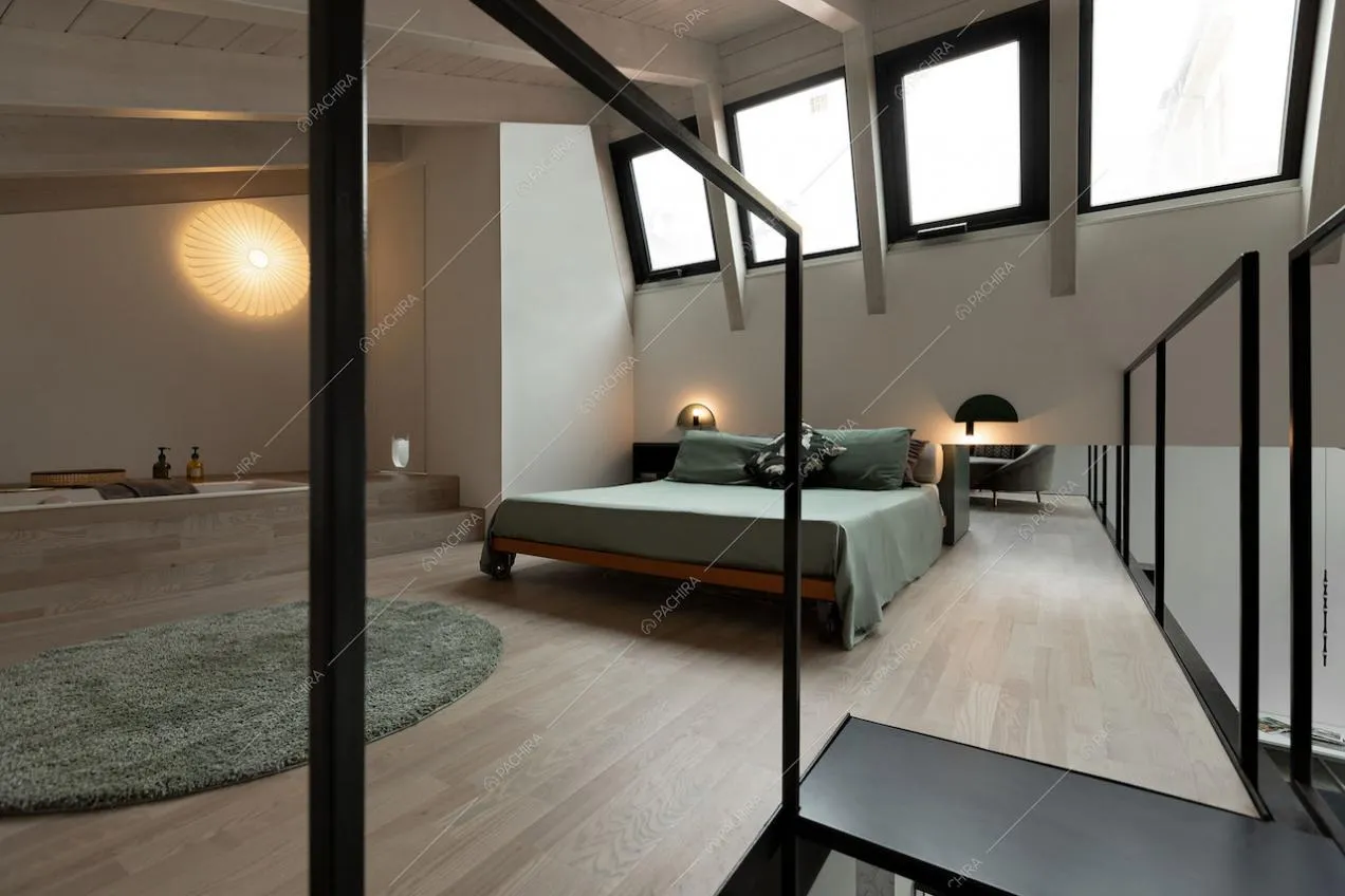 Ampia camera da letto matrimoniale con vasca a vista, lucernari e pavimento in parquet