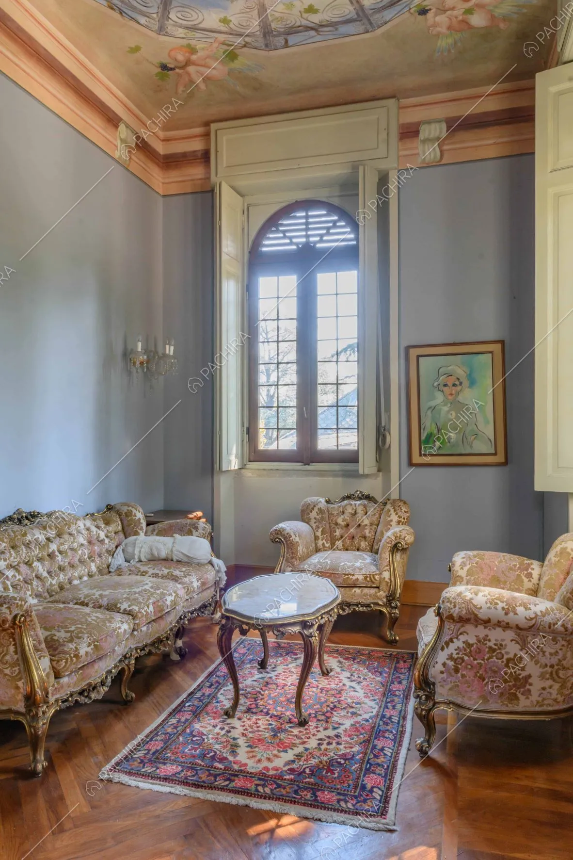 Salotto dal soffitto affrescato, con pavimento in parquet a spina di pesce e pareti azzurre