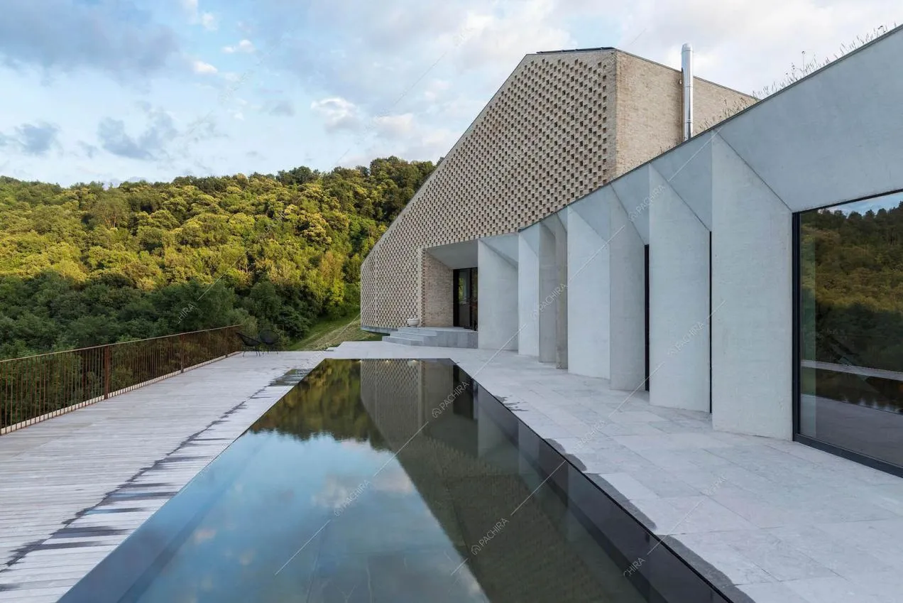 Piscina con fondo mobile sulla terrazza, grandi vetrate, esterni bianchi e in mattoni rossi a vista