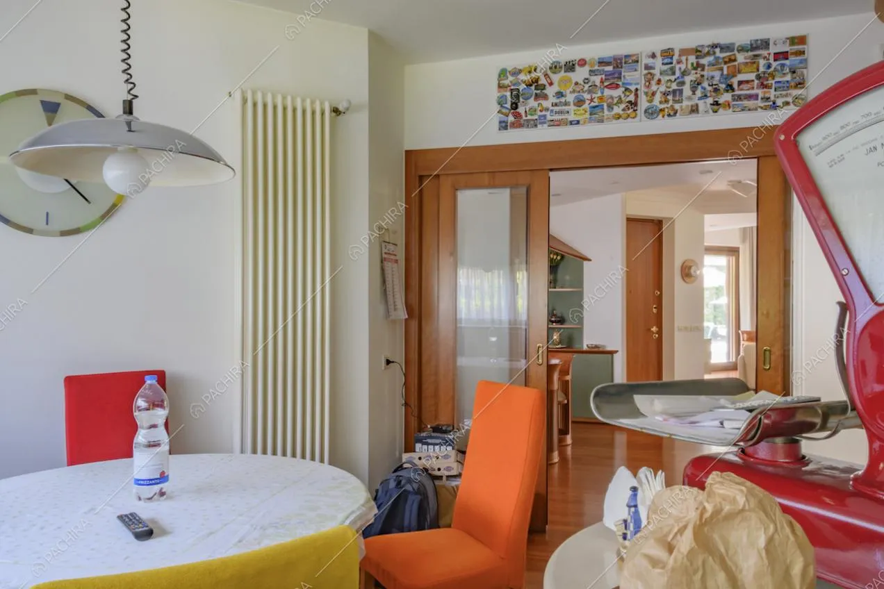 Tavolo da pranzo nella cucina dalle pareti bianche e porta scorrevole in vetro