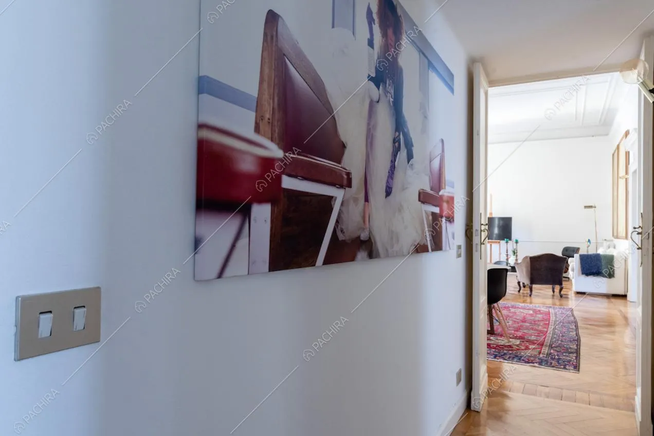 Dal corridoio con pareti bianche vista sul salotto con pavimento in parquet
