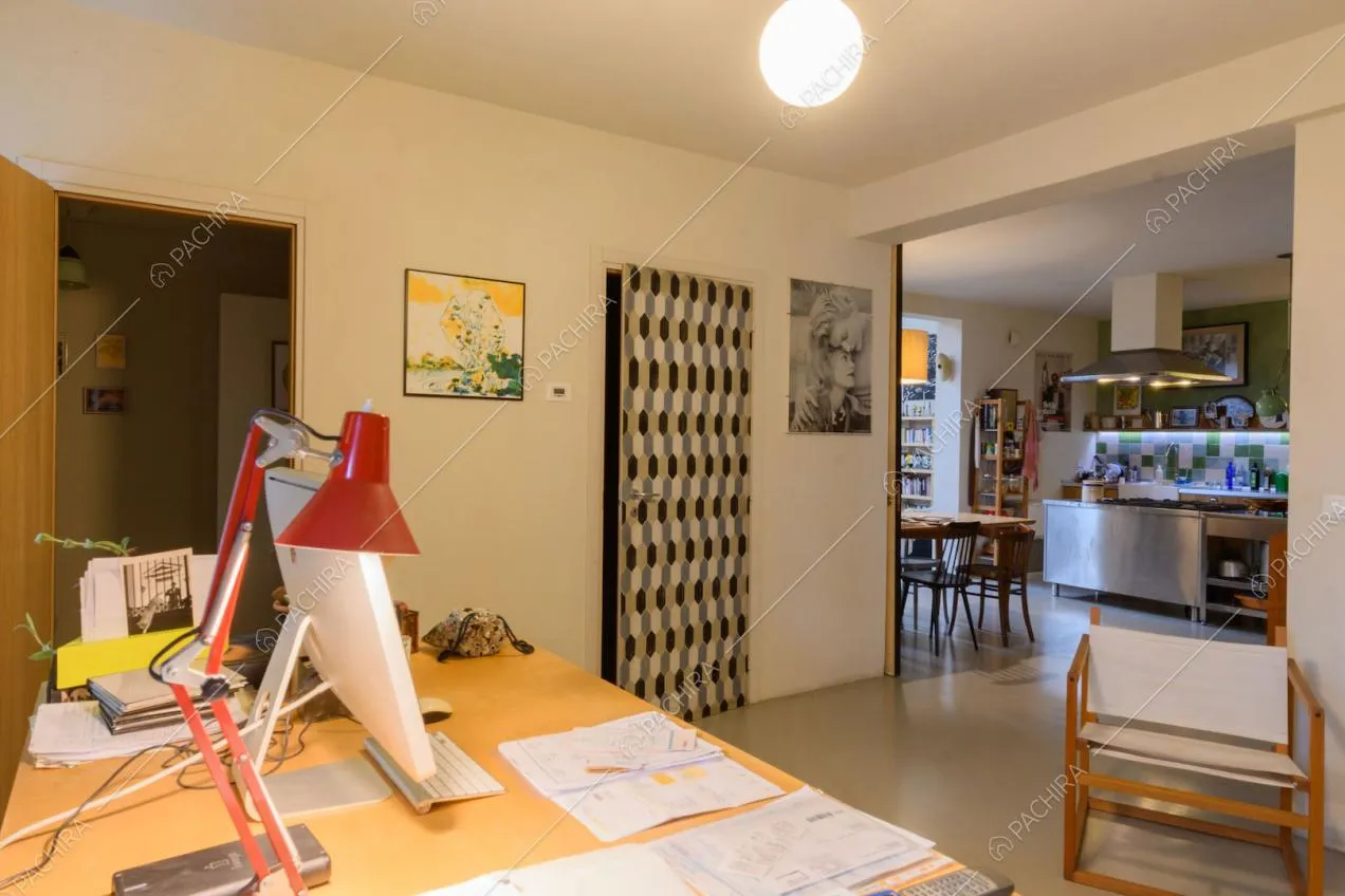 Dalla scrivania nello studio con pareti bianche vista sulla cucina con isola