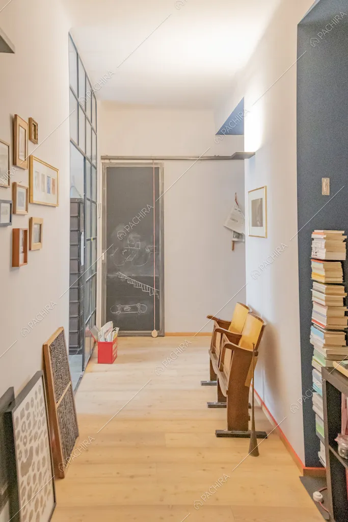 Corridoio con parquet, pila di libri e quadri appoggiati per terra