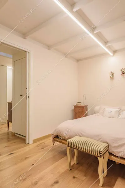 Camera da letto matrimoniale con pareti bianche e travi a vista sul soffitto