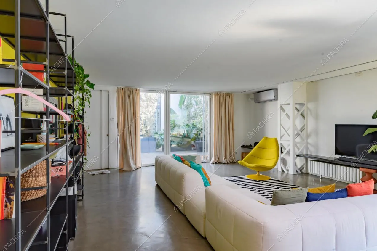 Divano angolare bianco nella luminosa zona living con porta-finestra e vista sulla terrazza