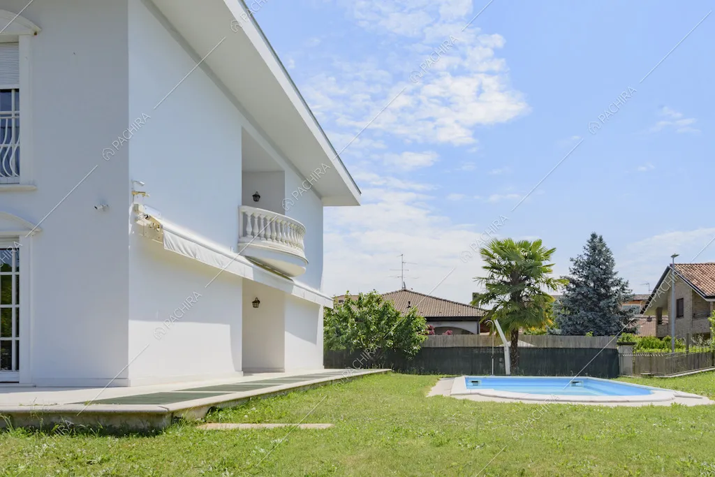 Facciata laterale della villa con balcone, tenda da sole e piscina