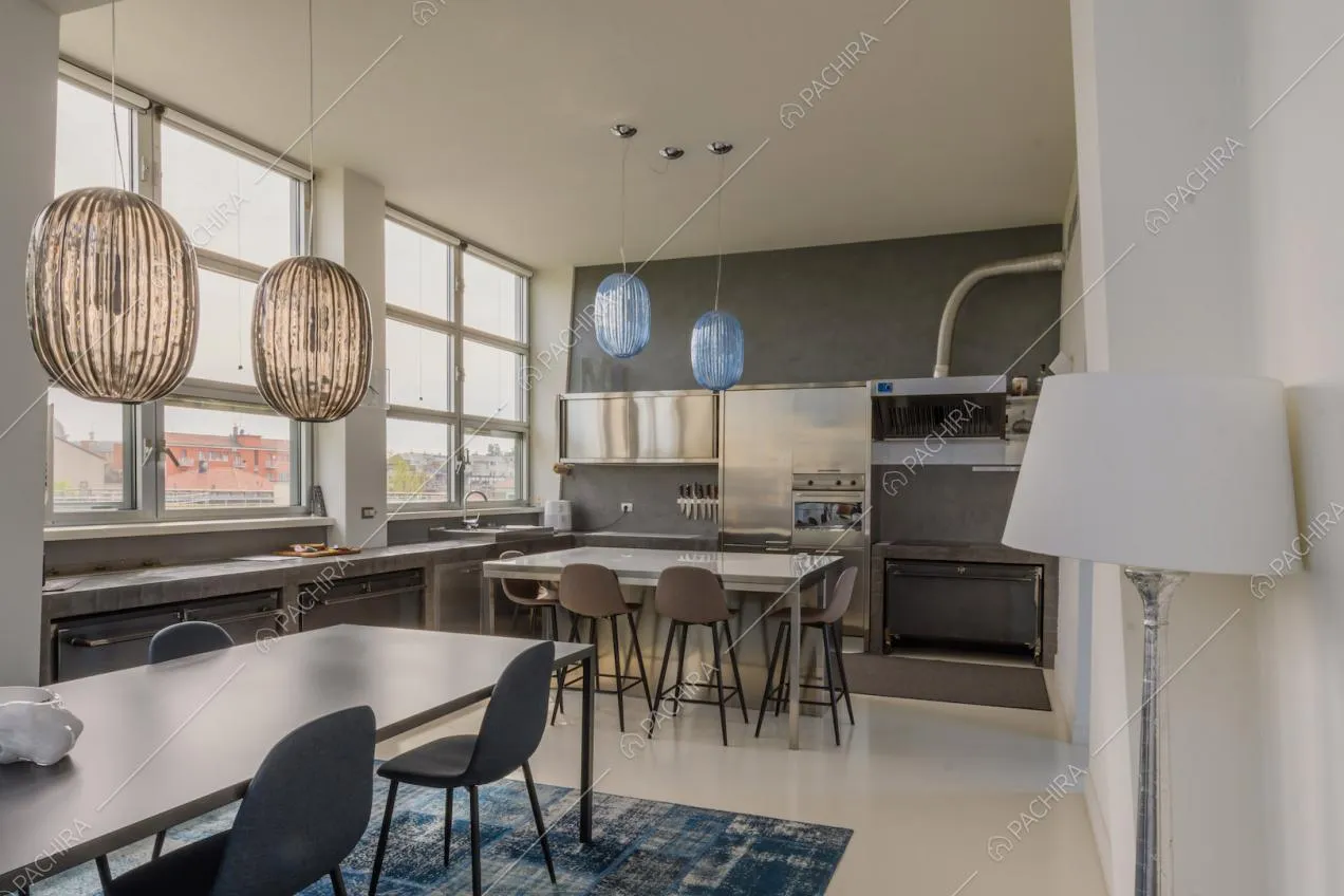Lampadari ovali di design nella cucina con parete grigia e fornelli a induzione